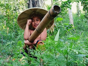 Portrait of shirtless boy holding stick at forest