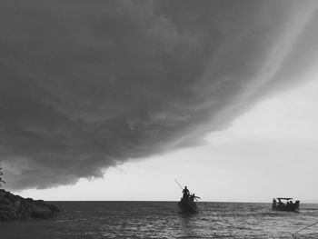 Silhouette man in boat on sea against sky