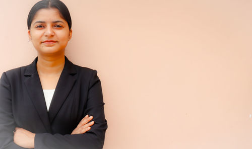 Portrait of a young woman standing against wall