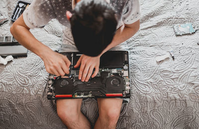 A young man is changing the thermal paste on a laptop.