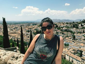 Portrait of woman wearing sunglasses against townscape