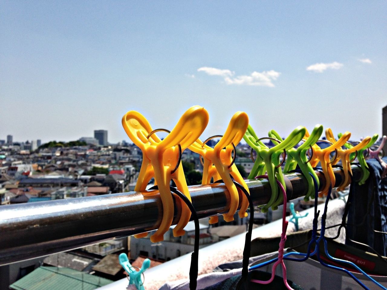 sky, creativity, art and craft, art, sunlight, multi colored, outdoors, blue, animal representation, day, large group of objects, clear sky, no people, human representation, sculpture, yellow, focus on foreground, metal, in a row, close-up