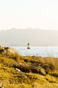 Scenic view of lighthouse in sea against mountain range