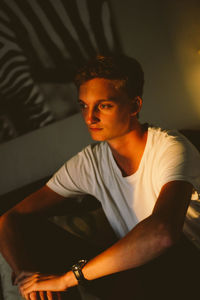 Portrait of young man sitting on sofa at home