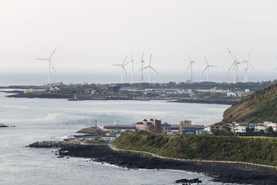 Traditional windmill by sea against sky