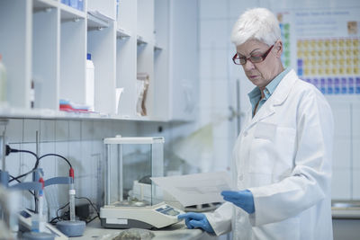 Senior woman in lab looking at paper