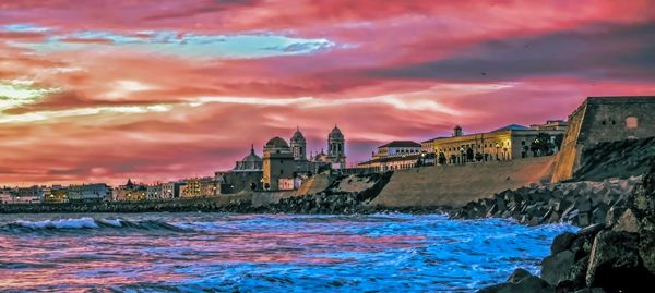 View of buildings at waterfront against cloudy sky