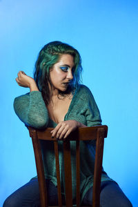 Young woman looking away while sitting on chair