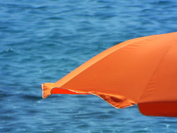 Close-up of orange parasol against sea