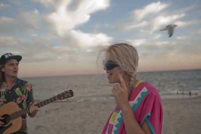 Friends playing music together on a beach