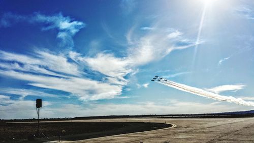 Low angle view of airplane flying over landscape against blue sky