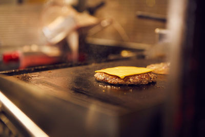 Hamburger with cheddar on top cooking on grill