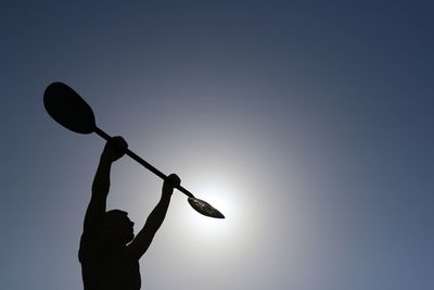 Low angle view of silhouette man playing basketball against sky