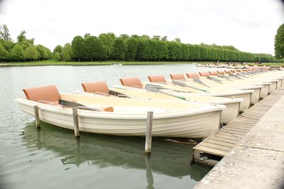 Row of boats moored in lake against sky