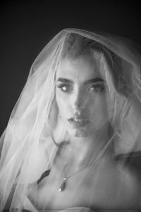 Portrait of young woman against black background