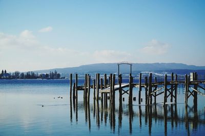 Wooden posts in sea against sky