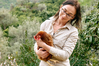 Woman holding brown hen in her hands in the farm. free-grazing domestic hen on organic farm.