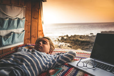 Boy sleeping by laptop in car