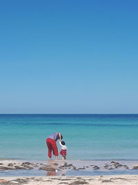 Father and daughter at beach against clear sky
