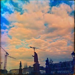 Low angle view of crane against cloudy sky