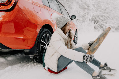 High angle view of man lying down on snow covered car