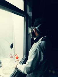 Side view of man looking through window