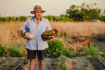 Portrait of man wearing hat standing on field