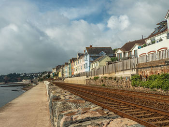 Railroad tracks by buildings in city against sky