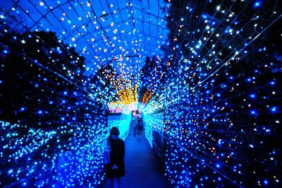 Man with illuminated lights against sky at night