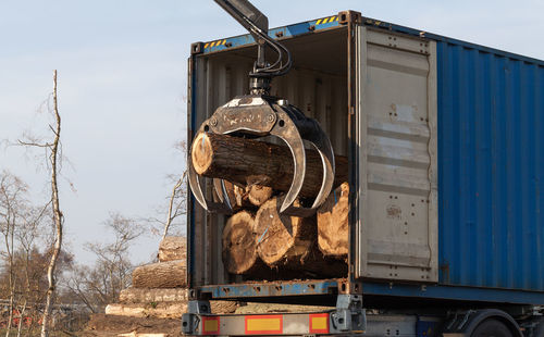 Crane loading logs at truck lumberyard