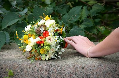 Midsection of person holding bouquet of flowering plant