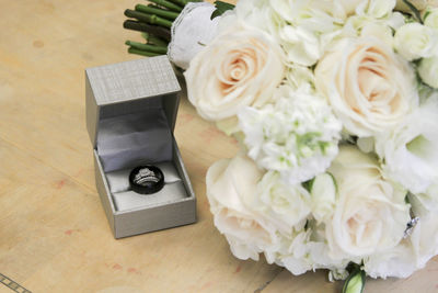 High angle view of rose bouquet and wedding rings on table