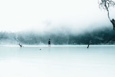 Rear view of backpacker standing at beach during foggy weather