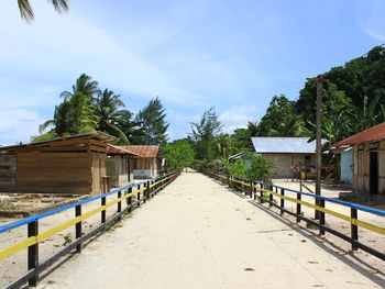 Footpath amidst trees and buildings against sky