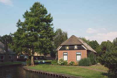 House by trees and building against sky