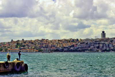 Sea by cityscape against sky