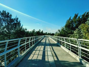 Footbridge amidst trees against sky