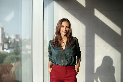 Beautiful young woman standing against wall