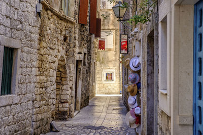 Woman walking on narrow alley amidst buildings in city