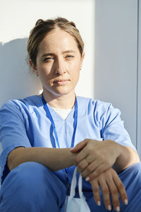 Doctor wearing scrubs resting in front of wall