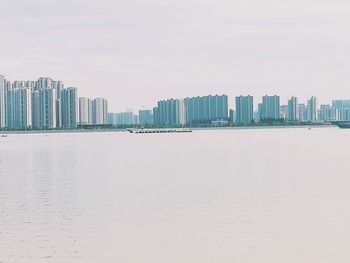 Sea by cityscape against sky