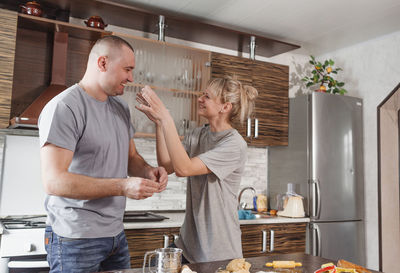 Friends standing in kitchen at home