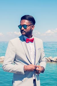 Young man wearing sunglasses standing against sky