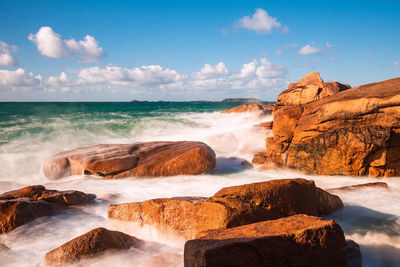 Scenic view of rocks on beach against sky