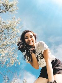 Portrait of smiling young woman against sky