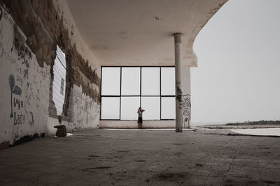 Mid distance view of person standing against window at abandoned building