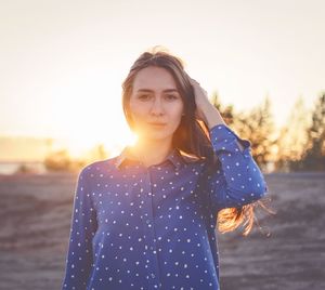 Portrait of young woman standing against clear sky