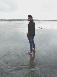 Full length portrait of young man standing on beach