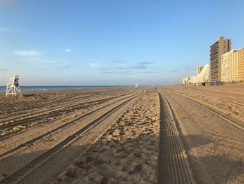 Tire tracks on beach against sky in city