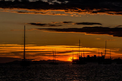 Silhouette sailboat sailing on sea against sky during sunset